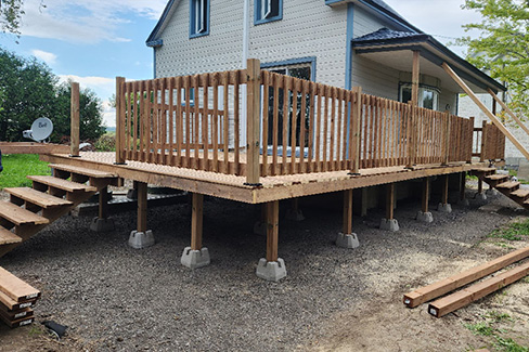 Construction d'un patio en bois traité avec balcon et escaliers